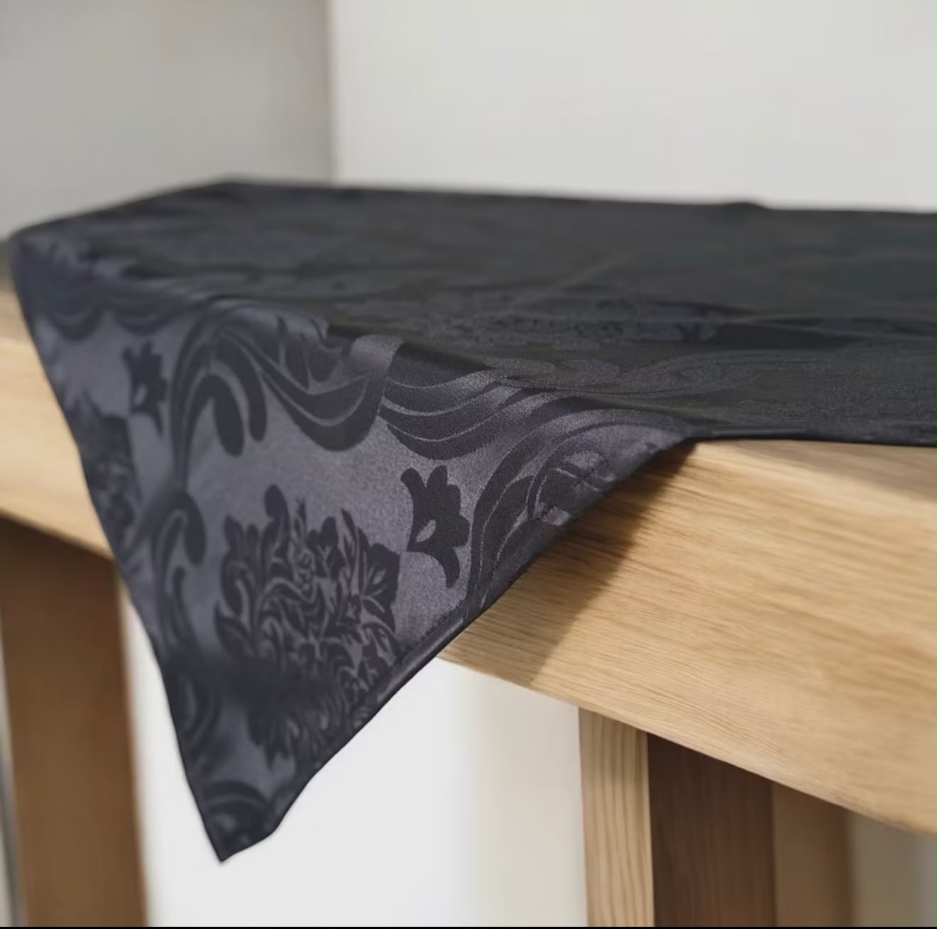 Toalha preta para ritual com textura floral sobre mesa de madeira